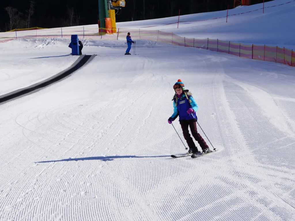 Skifahrerin fährt neben dem Förderband talwärts.
